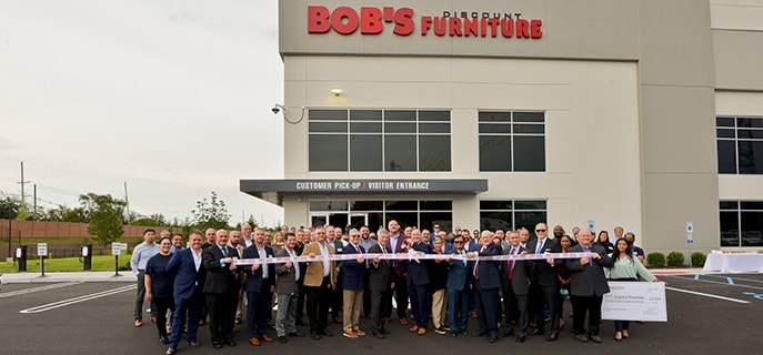 Several members of Bob's Discount Furniture's senior leadership team including CEO Bill Barton pose with Piscataway Mayor Brian Wahler at ribbon cutting ceremony for new Piscataway distribution center.